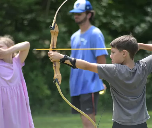 boy and girl practicing archery outside