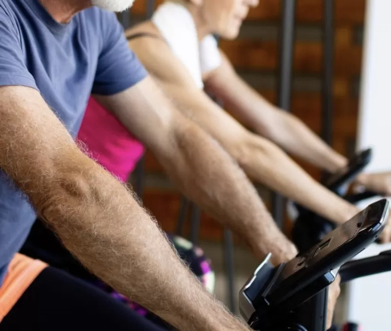 Man and woman riding cycling bikes in gym location